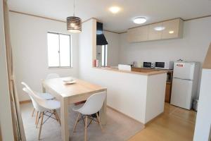 a kitchen with a wooden table and white chairs at iruka - Vacation STAY 83037v in Nago