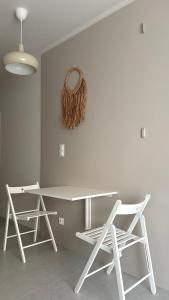 a white table with two chairs and a wreath on the wall at Sandy Apartment Dzwinów 3 Sand and Dunes Sauna Grota Solna Siłownia in Dziwnów +2 photos