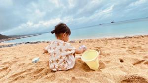 a baby sitting in the sand on the beach at iruka - Vacation STAY 83037v in Nago