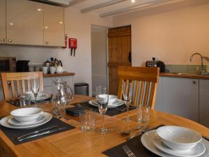 a wooden table with plates and wine glasses on it at Uk47758 - Horseshoe Cottage in Launceston