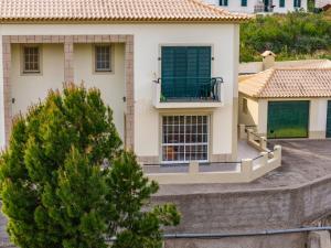 a house with a green shutter on a balcony at Simões Charm By HR Madeira in Vila Baleira