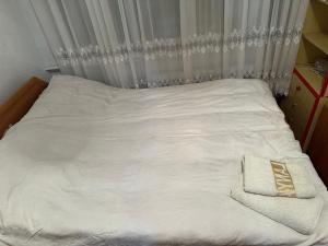 Una cama con sábanas blancas y una toalla. en Aport 24, en Karakol