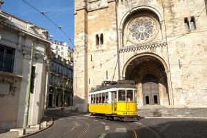 a yellow tram on a street in front of a building at Portas da Sé Apartments in Lisbon +16 photos