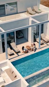 deux personnes assises sur une maison avec piscine dans l'établissement Seadream Villa, à Lakhania