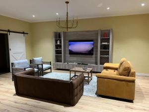 a living room with couches and a flat screen tv at The Cozy Nook in Blantyre