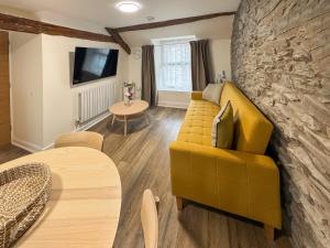 a living room with a yellow couch and a stone wall at Apartment Two - Uk49592 in Bala