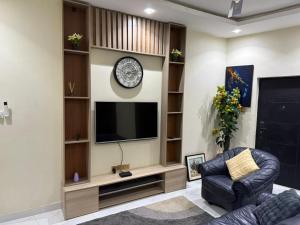 a living room with a television and a clock on a wall at Jayda Lodge in Kwedonu