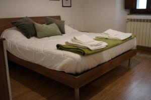 a bed with white sheets and green towels on it at Milton House in Arezzo