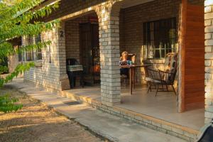 eine Frau sitzt auf einer Terrasse auf einem Haus in der Unterkunft Mackers Self Catering Cottages in Hazyview
