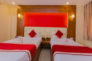 two beds in a hotel room with red walls at OYO 160 Hotel Shraddha Palace in Kathmandu