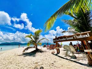 a beach with a palm tree and a sign on it at D&A Paradise Villas in Koh Samui