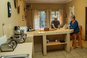 Ein Mann und eine Frau sitzen an einer Küchentheke in der Unterkunft Mackers Self Catering Cottages in Hazyview
