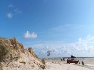 a red van parked on a sandy beach with a kite at 7 person holiday home in Fanø-By Traum in Fanø