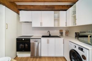 Una cocina con gabinetes blancos y lavadora y secadora. en WHome Relaxed Stay in Central Oeiras, en Oeiras 1 foto más