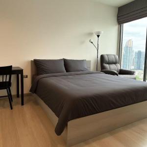 una camera da letto con un letto, una sedia e una finestra di BTS Thonglor Skyline Condo a Bangkok