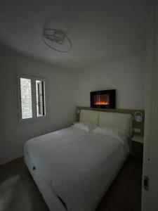 a bedroom with a white bed and a tv on the wall at La casa sul lago blu in Domaso
