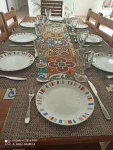 a table with plates and glasses on a table at casamarpenaareia in Búzios