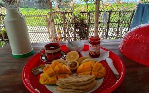 un plato rojo de comida en una mesa de madera en Hakuna Matata Bungalows, en Jambiani