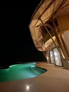 une piscine la nuit avec un grand parasol dans l'établissement Manta Villa - Frontbeach Bamboo Eco Villa - Kini Village, à Sekongkang