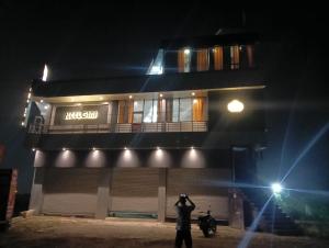 a man taking a picture of a building at night at hotel Neelgiri in Kichha +8 photos