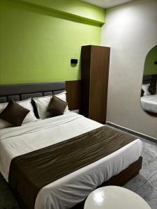 Un dormitorio con una cama grande con una pared verde. en Shiv hotel, en Ahmedabad