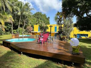 a wooden deck with chairs and a table next to a pool at Le Figuier De Barbarie in Sainte-Rose