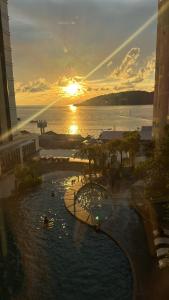 a view of a pool at a resort with the sunset at The Shore Kota Kinabalu by Ems Executive Suites Seaview in Kota Kinabalu