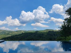 a swimming pool with clouds in the sky and trees at Villa Andrea in Rodello