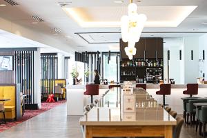 un restaurante con una mesa larga y un bar en OSKO Hôtel Toulouse Aéroport, en Blagnac
