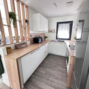 a kitchen with white cabinets and a wooden counter top at Maison individuelle in Harfleur