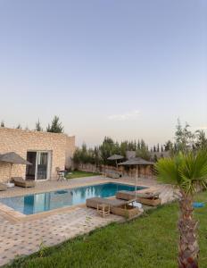 Una piscina con tumbonas y sombrillas al lado de una casa. en Mood Villa Essaouira, en Essaouira