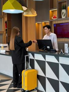 a man and a woman shaking hands at a counter at Ibis Aktobe in Aktobe