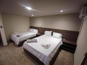 a hotel room with two beds and a television at Hotel Cadiz IN in Ibagué