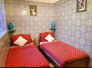 two beds in a room with red and white sheets at riad la citadelle in El Jadida
