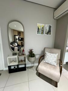 a living room with a chair and a mirror at Estanconfor Praia Santos 3 - AC garagem arrumação sacada fechada in Santos +20 photos