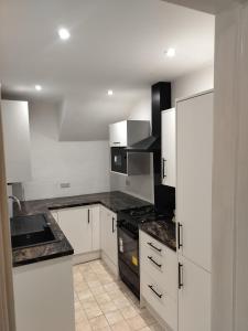 Una cocina con gabinetes blancos y encimeras negras. en Kai Homes in Ashington, en Ashington