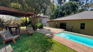 un cortile con piscina e terrazza in legno di Casa 23 Floresta Boa Vista - 4 Suítes e Piscina Aquecida em Meio à Natureza a Teresópolis