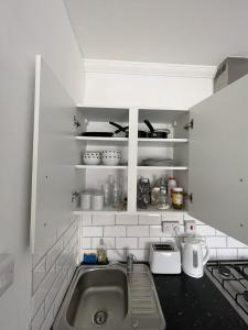 a kitchen with a sink and a shelf with pots and pans at Entire Cosy Flat in Central London in London