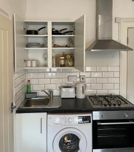 a kitchen with a sink and a washing machine at Entire Cosy Flat in Central London in London +2 photos
