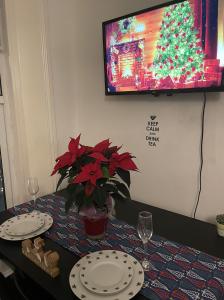a table with plates and glasses and a christmas tree at Entire Cosy Flat in Central London in London