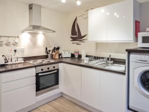 a kitchen with white cabinets and a sink at The Snug, Lynmouth - Uk41696 in Lynmouth