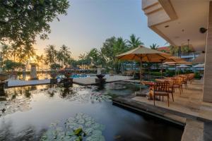 una piscina in un resort con tavoli, sedie e ninfee nell'acqua di Conrad Bali a Nusa Dua
