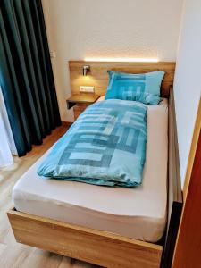 a bed with blue sheets and a wooden head board at Gasthaus Linde Ingelfingen in Ingelfingen +12 photos