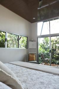 a bedroom with a bed and a chair and windows at The Emerald Haven in Parrita
