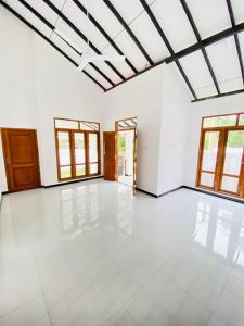 a large empty room with windows and a ceiling at Himeth's Residence in Weliweriya