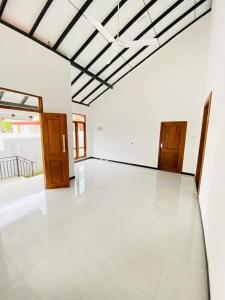 an empty room with a white floor and wooden doors at Himeth's Residence in Weliweriya