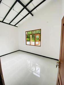 an empty white room with a window in it at Himeth's Residence in Weliweriya