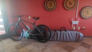 a bike is parked against a red wall at Petit Thay Home in Cumbuco