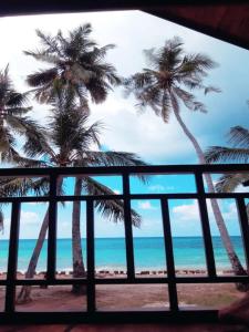 a view of the beach and palm trees from a window at Villa Mangunrahe in Bira