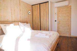 a bedroom with a white bed with towels on it at La Licorne de l'Encombrette 150 m2 in Allos